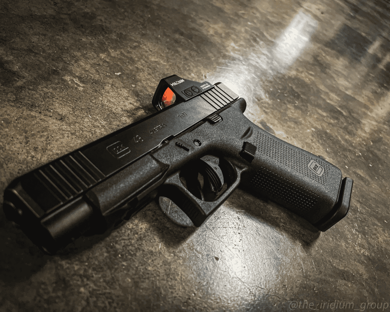 Semi-automatic handgun with a red-dot sight on a concrete floor
