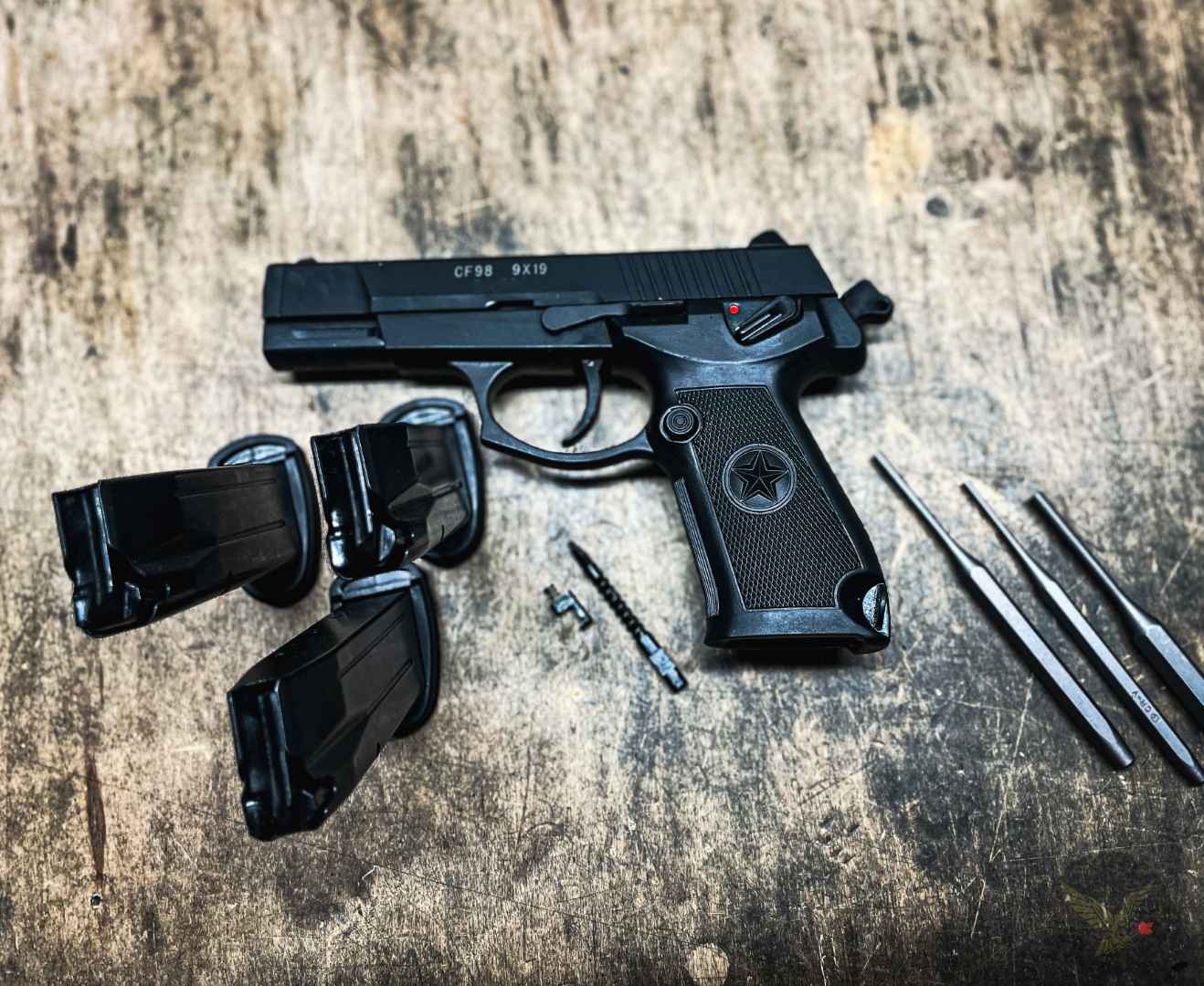 Disassembled handgun, magazines and cleaning rods on a bench