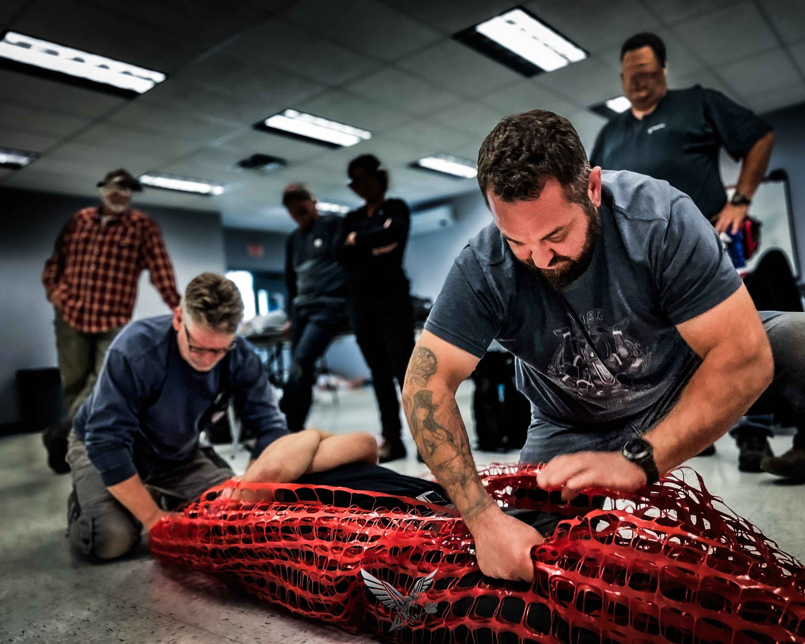 Instructor coaching students through bleeding control on a trainer in a classroom
